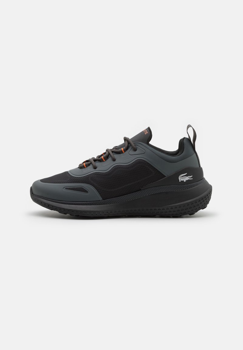 Chaussure de sport noire avec des accents gris, une tige en mesh texturé, des lacets orange contrastants et une semelle en caoutchouc épaisse dotée d'un motif de crampons.