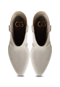 Botas de tobillo de color gris claro con punta afilada, textura de ante suave y diseño minimalista. Presenta un logo sutil en dorado en la plantilla.