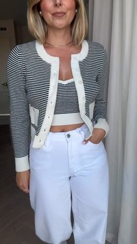 Cardigan às riscas preto e branco com botões e bolsos, usado sobre um top cropped combinando, acompanhado de calças brancas de subida alta.