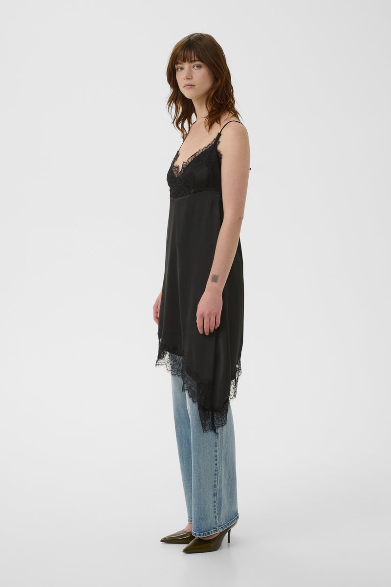 Μαύρο μεταξωτό φόρεμα σε στυλ slip με δαντέλα στο τελείωμα και το λαιμό, με λεπτές τιράντες και άνετη εφαρμογή, συνδυασμένο με απαλά μπλε τζιν με ίσια μπατζάκια.