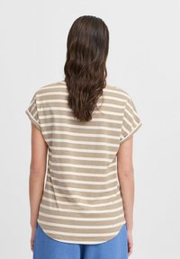 T-shirt léger à manches courtes rayé beige et blanc, avec une coupe décontractée et un ourlet arrondi. Texture en coton doux.