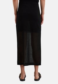 Schwarzer Maxirock mit transparenter Textur, gerader Form und elastischem Bund, der einen undurchsichtigen oberen Abschnitt und einen halbtransparenten unteren Teil aufweist.