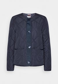 Marinblå quiltad jacka med rund hals, två framfickor och stora knappar längs mitten, med en slät yta och en figurnära design.
