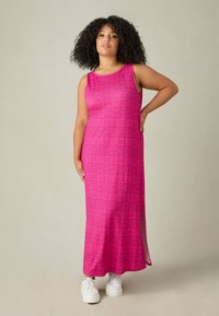 Różowa, bezrękawnikowa sukienka maxi z teksturowanym wzorem geometrycznym, bocznym rozcięciem i luźnym krojem, zestawiona z białymi sneakerami.