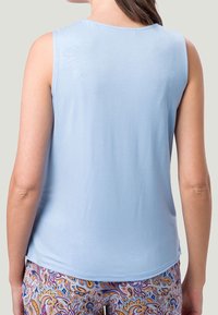 Haut sans manches bleu clair avec un col arrondi, présentant une texture lisse. Associé à un bas coloré à motifs avec un design paisley.