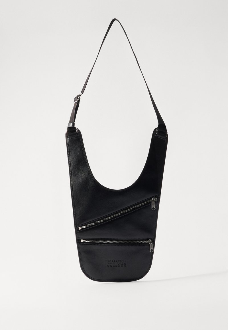 Borsa a tracolla in pelle nera con forma curva, caratterizzata da due cerniere diagonali e dettagli in rilievo alla base. Include una tracolla regolabile.