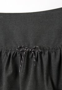 Falda gris oscuro hecha de tejido suave, con una cintura fruncida y un cordón negro y blanco para un ajuste ajustable.