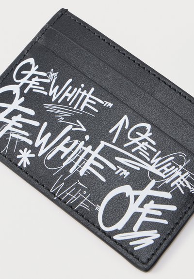 Μαύρο δερμάτινο πορτοφόλι καρτών με πολλαπλά άσπρα σχέδια σε στυλ γκράφιτι με τις λέξεις "OFF-WHITE" και βέλη τυπωμένα στο μπροστινό μέρος.