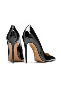 Zapatos de tacón alto para mujer de charol negro con punta puntiaguda, tacones de aguja y suelas beige, mostrados desde ángulos frontal y posterior.