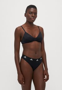 Black bikini set with a triangle cup top and low-rise briefs. Fabric is smooth, features branded elastic band on the waist.