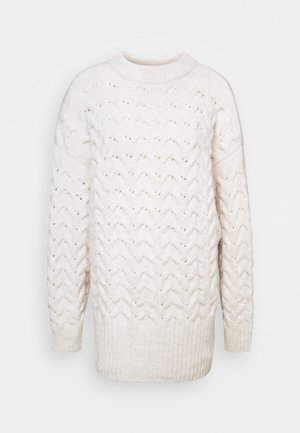 Cream-colored knitted sweater with a textured zigzag pattern, ribbed hem, and round neck. Made from soft, warm material. Loose fit.