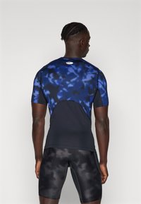 Korte mouwen sportshirt in donkerblauw met een wolkachtige patroon, gecombineerd met zwarte fitted shorts met een subtiele textuur.