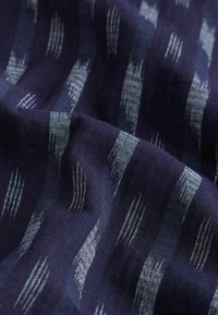 Marine stof met zilveren abstracte strepen; zachte textuur, geweven patroon met variërende dikte, toont een mix van donkere en lichte tinten.