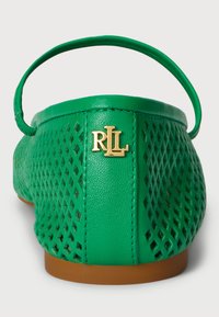 Žalios perforuotos plokščios bateliai su auksiniu logotipu šone. Turi lankstų dirželį ir lygią pėdos dalį. Tekstūruotas dizainas ir lengvas medžiaga.