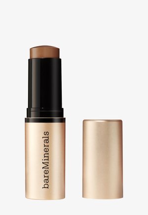 Fond de teint en crème BareMinerals en teinte beige moyen, tube noir et doré avec le capuchon doré retiré, sur fond blanc.