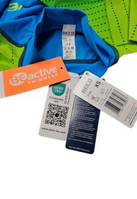 BECO aktive Schwimmbekleidung mit blauem und grünem Design, einschließlich Pflege- und Größentags, Oeko-Tex-Zertifizierung und einem QR-Code für Informationen.