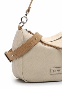 Beige leren handtas met een gestructureerde afwerking, voorzien van een bruine verstelbare hengsel met de gravure "SURI FREY" en zilveren hardware accentueringen.
