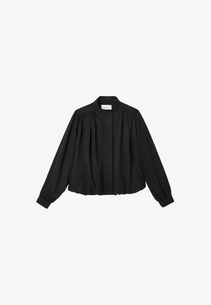 Blouse noire à manches longues avec empiècement froncé, col mandarin, fermeture par boutons et ourlet et poignets élastiqués, présentée sur fond blanc.