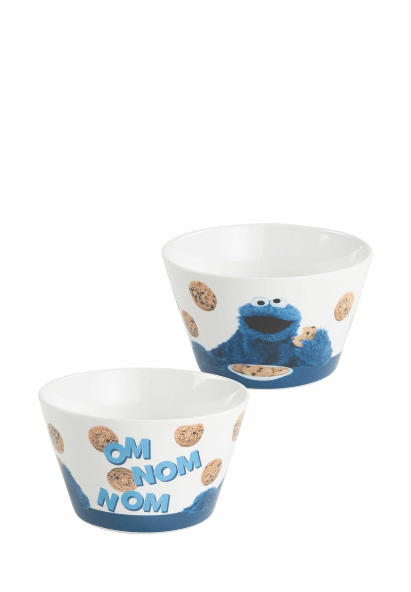 Ciotole in ceramica che presentano un personaggio blu con un biscotto, circondato da illustrazioni di biscotti e testo "OM NOM NOM" in blu, su uno sfondo bianco.