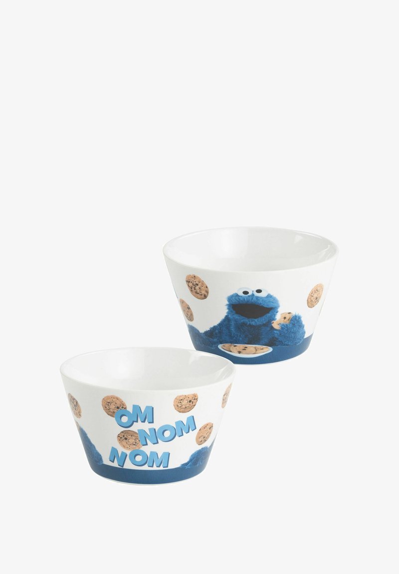 Ciotole in ceramica che presentano un personaggio blu con un biscotto, circondato da illustrazioni di biscotti e testo "OM NOM NOM" in blu, su uno sfondo bianco.