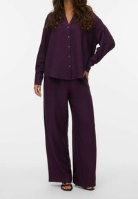 Purple button-up shirt with a V-neck and loose fit, paired with wide-leg matching pants, crafted from lightweight textured fabric.