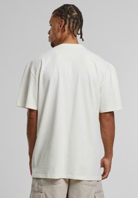 Oversized kremfarget bomulls t-skjorte med rund hals og korte ermer, med en jevn tekstur og uten synlige mønstre eller detaljer.