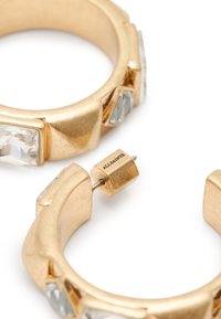 Boucles d'oreilles en or avec des pierres facettées transparentes et des finitions lisses. Les détails remarquables incluent des formes angulaires et un fermoir signé.