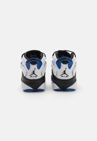 Bílé a černé sportovní tenisky s modrým akcentem, které mají texturovaný síťovaný svršek, výrazné logo a polstrovaný límec.