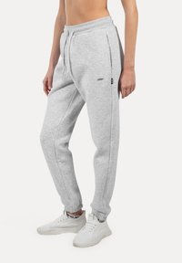 Lys grå sweatpants lavet af en bomuldsblanding. Har en elastisk talje med snor, sidelommer og tætsiddende ben.