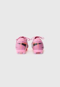 Pink soccer cleats with a textured surface, featuring black and orange accents, narrow fit, and multi-colored studs for traction.