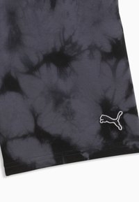 Tissu tie-dye noir et gris foncé avec logo Puma cousu en blanc dans le coin inférieur droit du matériau textile.