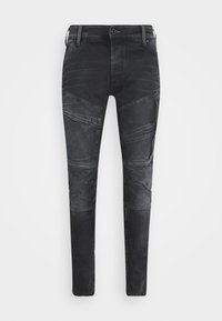 Svarta slim-fit jeans med sydda paneldetaljer och knäppta fickor på båda låren, framknapp och bältesöglor synliga.