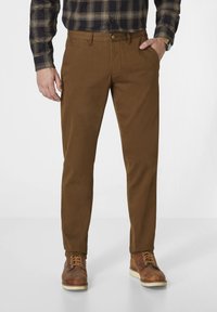 Brown trousers made of a smooth fabric, featuring a straight cut, flat front, and side pockets, paired with brown lace-up boots.