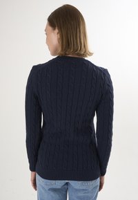 Pull en mailles torsadées de couleur marine avec ourlet et poignets côtelés, présentant des motifs texturés sur l'ensemble. Vue arrière montrant une silhouette ajustée et un col rond.