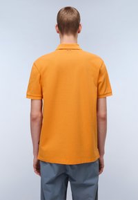 Kurzärmliges Poloshirt aus leuchtend orangefarbenem Stoff, mit einem Kragen, strukturiertem Oberfläche und dezenter Branding auf der Rückseite nahe dem Ausschnitt.