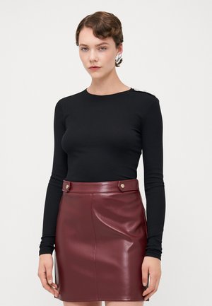 Svart langermet ribbestrikket topp med rund hals, kombinert med et burgunder faux skinn skjørt med gullknappe detaljer og en tight silhuett.