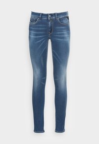 Jeans skinny en denim azul oscuro con un leve desvanecimiento. Cinco bolsillos, cierre de botón y pasadores para el cinturón, con detalles de costura en contraste.