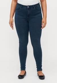 Dark blue skinny jeans with a high waist, featuring a button and zipper closure, five-pocket design, and a smooth denim texture.