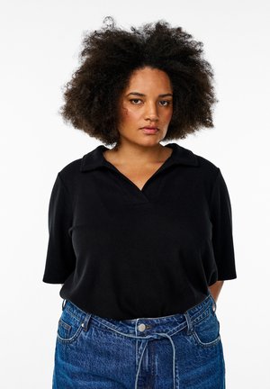 Schwarzes Poloshirt mit Kragen und kurzen Ärmeln, kombiniert mit hochgeschnittenen blauen Jeans. Glatte Stoffstruktur, einfaches Design.