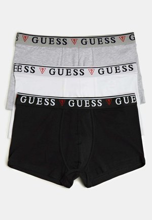 Boxer briefs bianchi in cotone con elastico nero recante il logo "GUESS". Il modello ha un fisico tonico ed è a torso nudo.