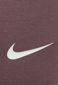 Αθλητικό ύφασμα της Nike σε σκούρο μπορντό με ραβδωτή υφή, που διαθέτει το χαρακτηριστικό λ ευκό λογότυπο swoosh.