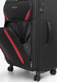 Czarna walizka na kółkach z czerwonymi akcentami, wykonana z twardego materiału, z podwójnym zamkiem błyskawicznym i zamkiem na kod, a także wyłożonym wnętrzem z wzorzystej tkaniny.