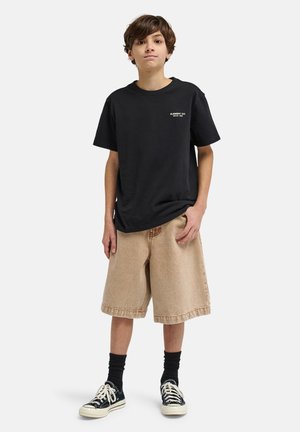 Czarny bawełniany t-shirt z białym logo, beżowe szorty jeansowe, czarne skarpetki i czarne sneakersy z białymi akcentami. Prosty, casualowy design.