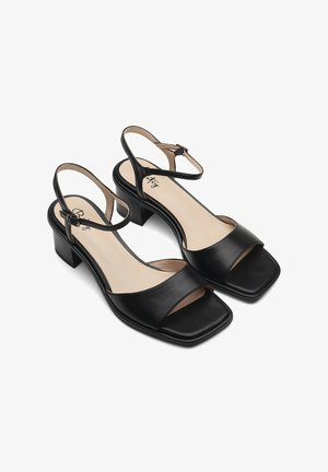 Black leather block-heeled sandals feature an open toe, square cut, and adjustable ankle strap with a smooth inner lining.
