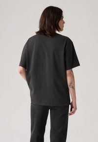 Camiseta de manga corta en gris oscuro, con un ajuste relajado y textura suave, que presenta un dobladillo redondeado y un diseño simple.