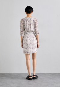 Floral dress with three-quarter sleeves, gathered neckline, fitted waist, and above-knee length. Light fabric in cream with purple floral pattern.