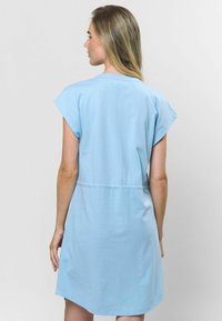 Šviesiai mėlynas, trumpomis rankovėmis sukniukas su suspaustu juosmeniu. Minkšta medžiaga, apvalus apatinis kraštas ir laisvalaikio stilius, tinkamas šiltam orui.