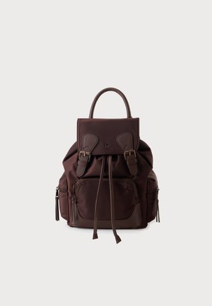 Sac à dos en cuir marron foncé avec une poche zippée avant, deux poches latérales zippées, un rabat supérieur avec des sangles à boucle et une poignée unique sur un fond uni.