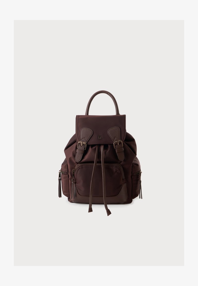 Sac à dos en cuir marron foncé avec une poche zippée avant, deux poches latérales zippées, un rabat supérieur avec des sangles à boucle et une poignée unique sur un fond uni.