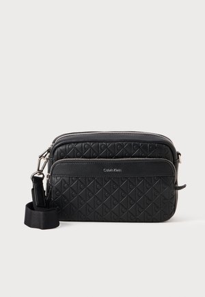Black leather crossbody bag with a quilted texture, featuring a zipper closure and adjustable strap. Logo printed on the front panel.